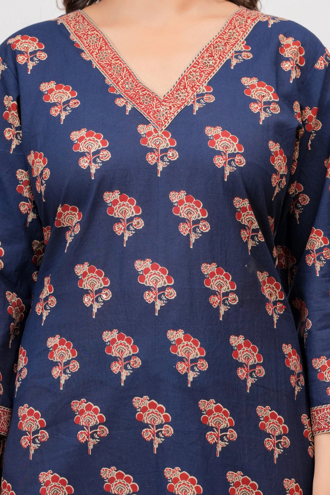 Woman wearing a navy blue cotton kurta with red floral handblock prints, matching zigzag patterned trousers, and a coordinating printed dupatta.