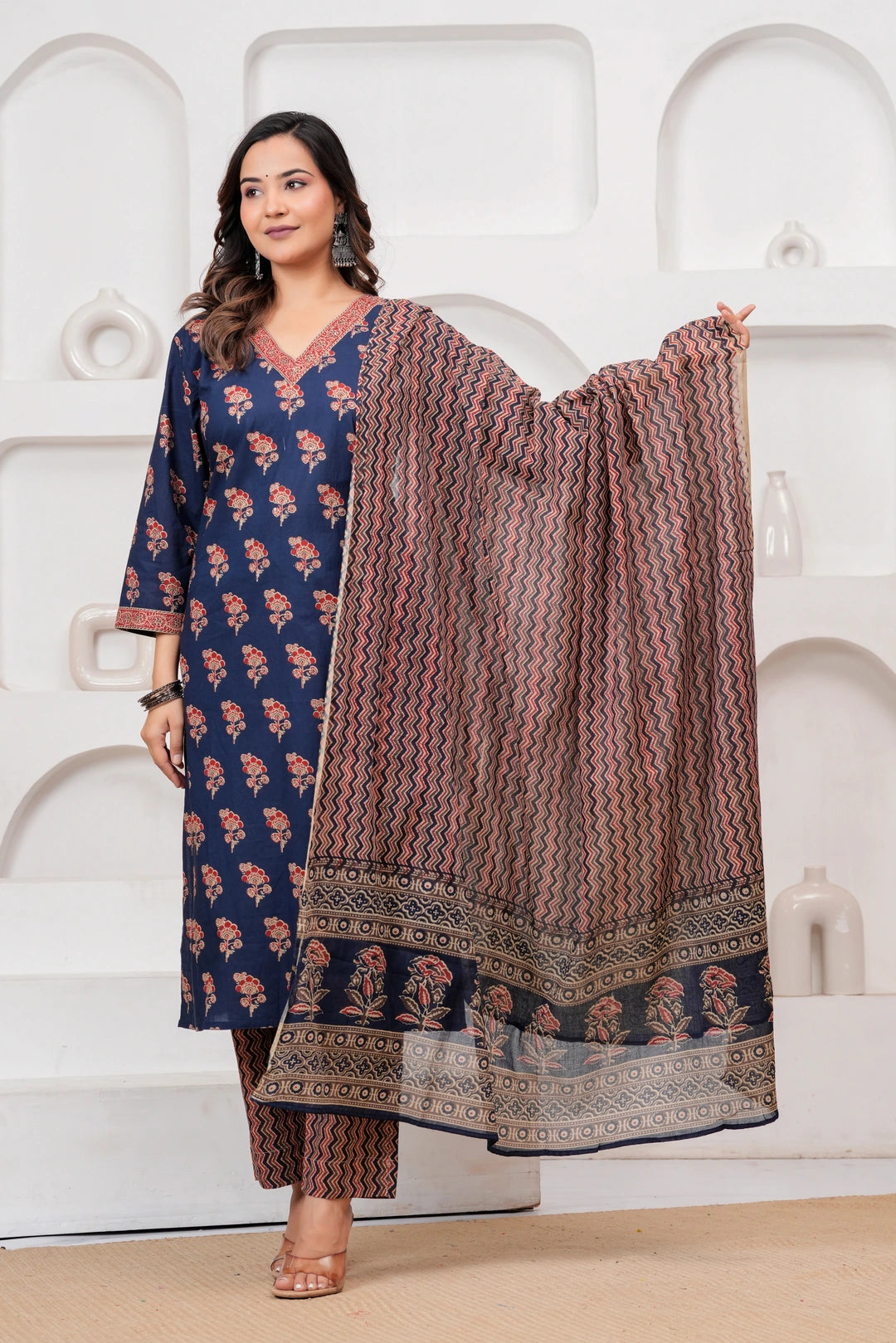Woman wearing a navy blue cotton kurta with red floral handblock prints, matching zigzag patterned trousers, and a coordinating printed dupatta.