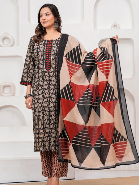Woman in a black handblock printed cotton kurta with red geometric dupatta and zig-zag printed pants standing against a white textured background.