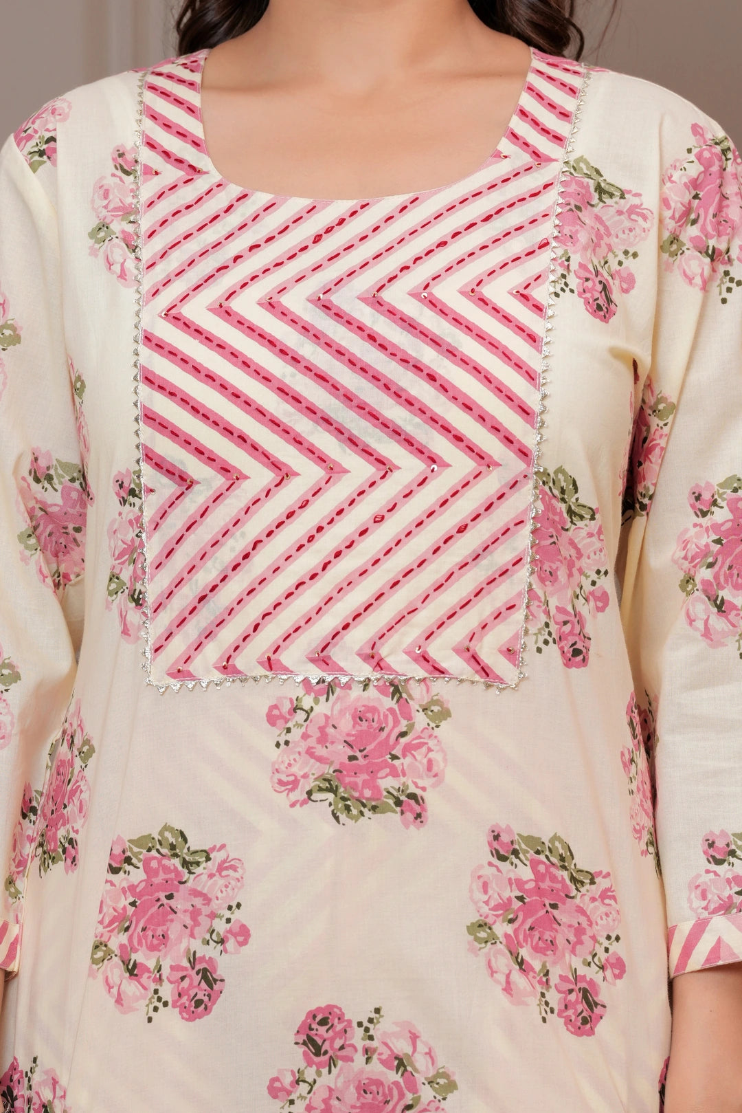 Woman in a cream-colored straight kurta with pink handblock floral prints and a chevron patterned pink leheriya dupatta.