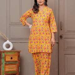 Woman wearing a yellow and pink floral handblock print cotton co-ord set with a V-neck kurta and straight pants.