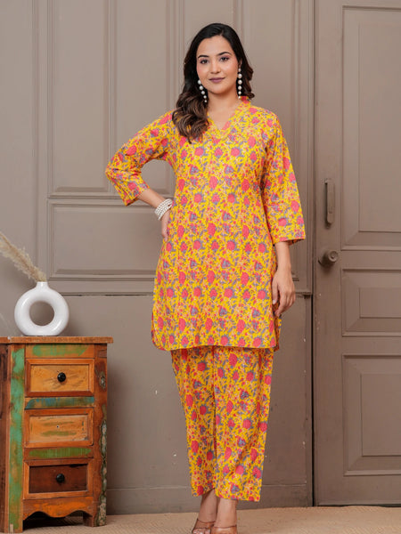 Woman wearing a yellow and pink floral handblock print cotton co-ord set with a V-neck kurta and straight pants.