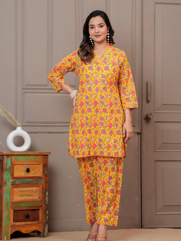 Woman wearing a yellow and pink floral handblock print cotton co-ord set with a V-neck kurta and straight pants.