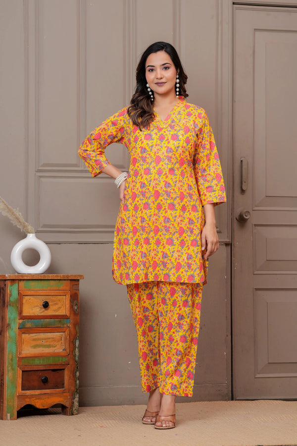 Woman wearing a yellow and pink floral handblock print cotton co-ord set with a V-neck kurta and straight pants.