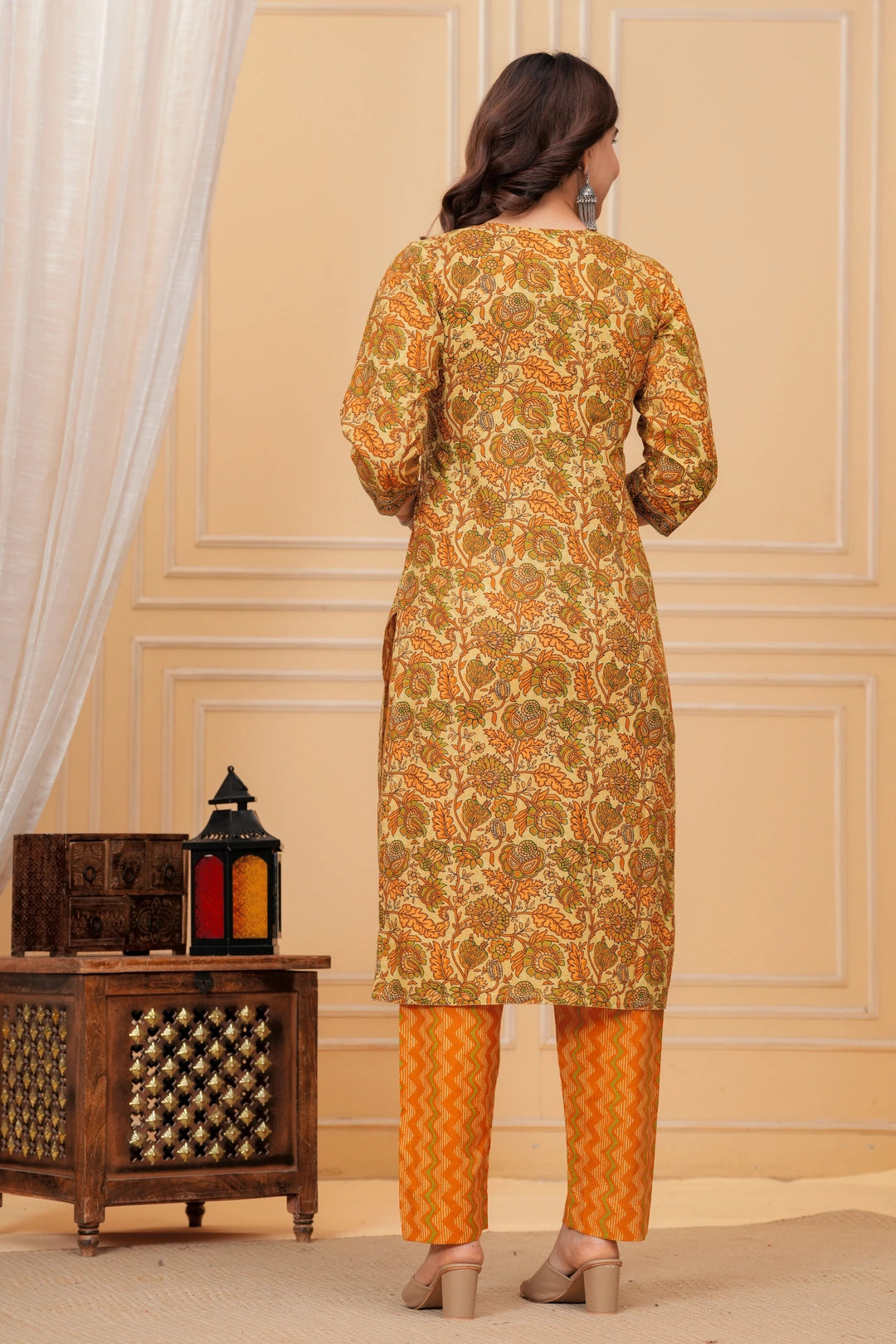 Woman wearing a mustard yellow floral handblock printed cotton kurta with orange zigzag pants set by Doriya Jaipur.