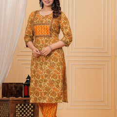 Woman wearing a mustard yellow floral handblock printed cotton kurta with orange zigzag pants set by Doriya Jaipur.