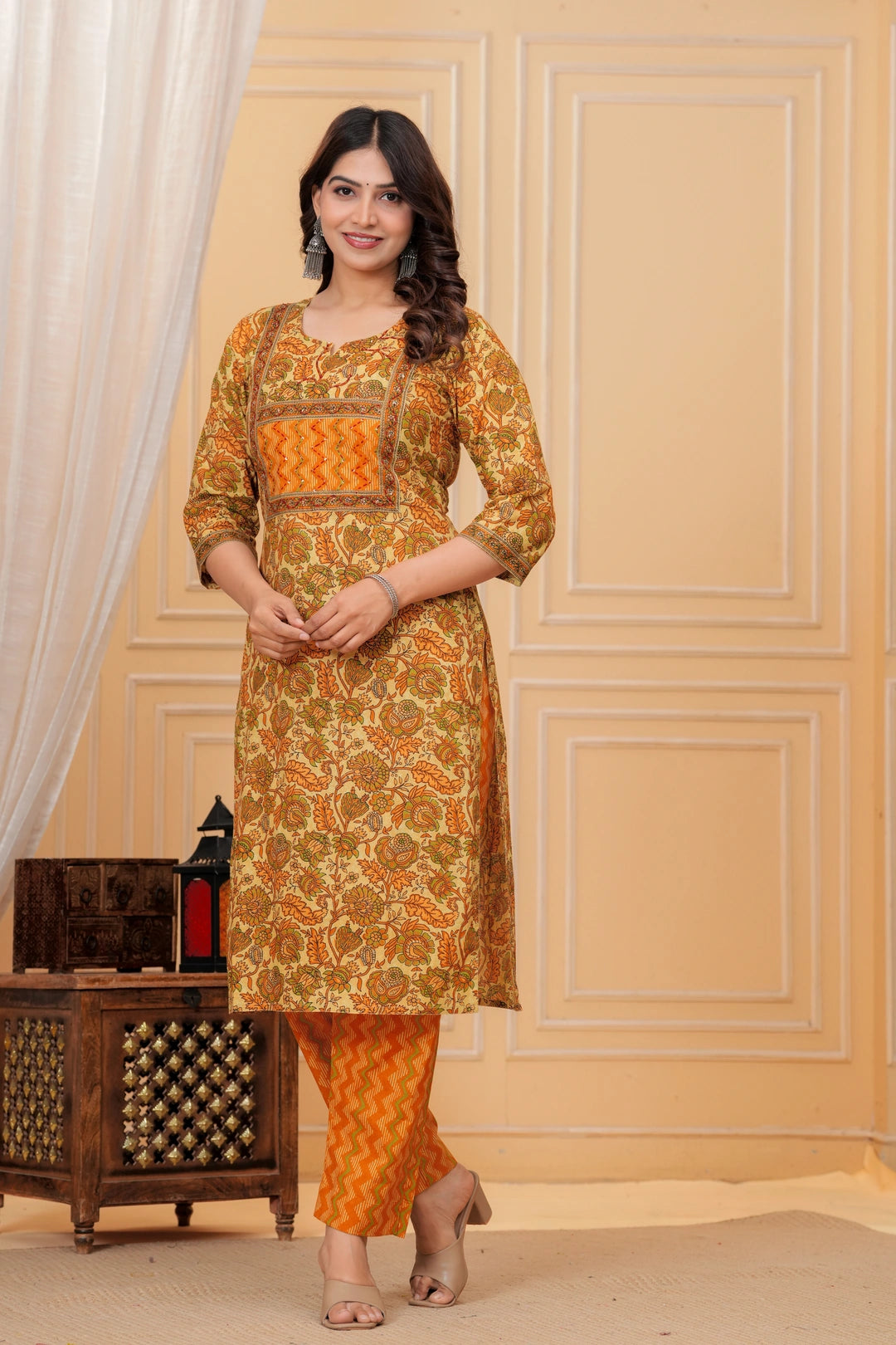 Woman wearing a mustard yellow floral handblock printed cotton kurta with orange zigzag pants set by Doriya Jaipur.