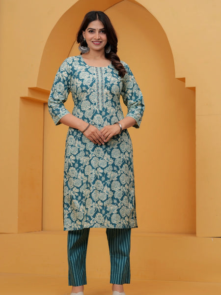 A woman wearing a teal blue cotton kurta with off-white floral handblock prints and teal vertical striped pants.