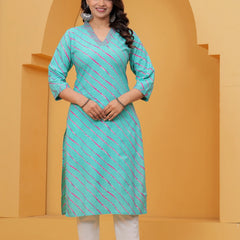 A woman wearing a vibrant turquoise blue straight-cut cotton kurta featuring pink and white diagonal Leheriya stripes, paired with white pants.