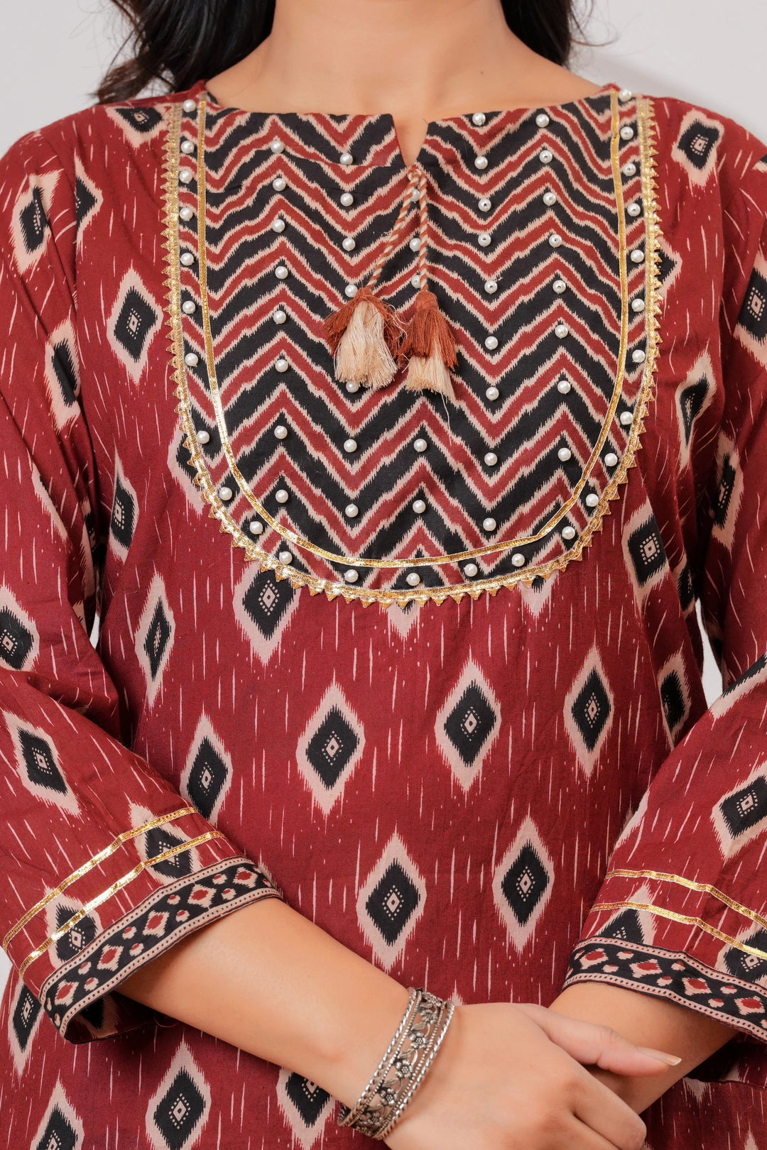 Woman wearing a maroon and black Ikat print cotton kurta set with a matching black dupatta and chevron trousers.